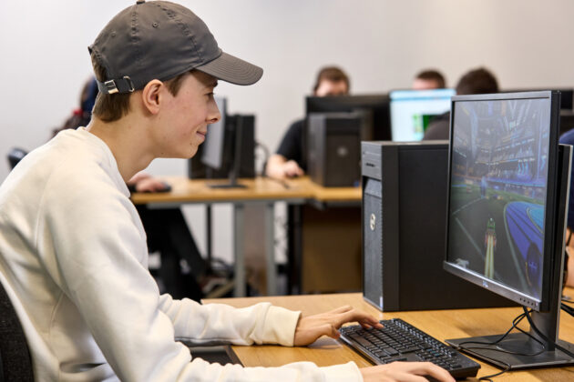 Photo of a student sat at a desk in a classroom playing a computer game