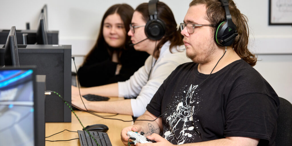 Photo of students wearing headphones and using a games consoles